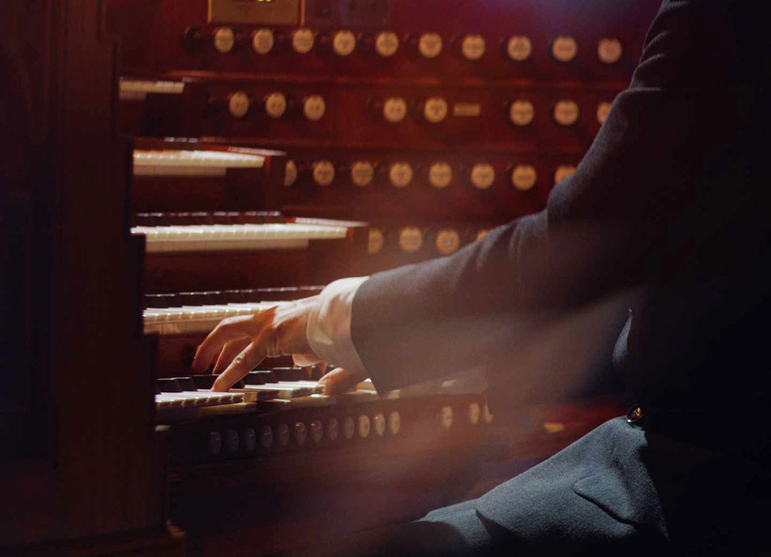 Kostymklädd man med vit skjorta. Ser vänstra handen på konsertpianist